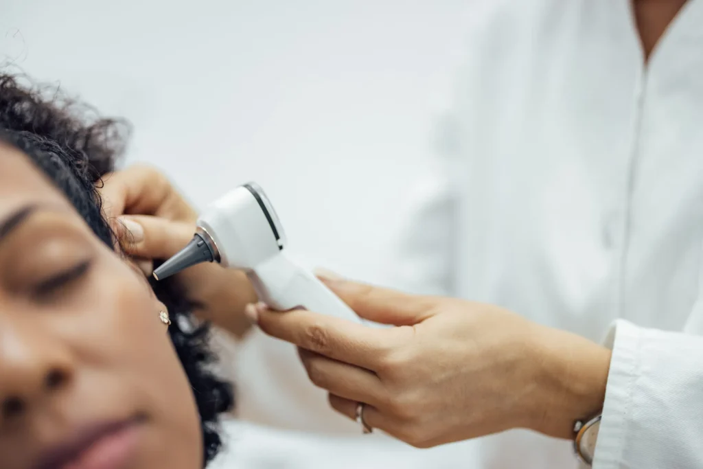 Audiologist examining a patient’s ear with an otoscope during a hearing evaluation at Minnesota ENT.