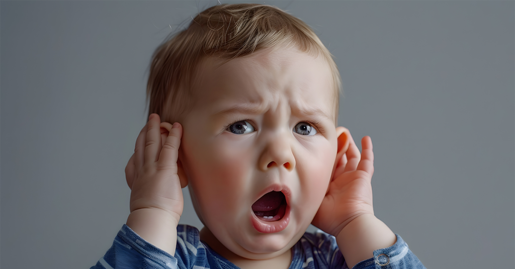 Sad toddler grabbing his ears, on the verge of tears