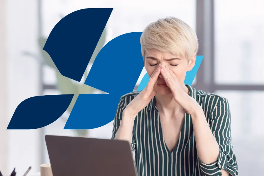 Woman experiencing sinus pressure and facial pain while working, a common symptom of chronic sinus infection